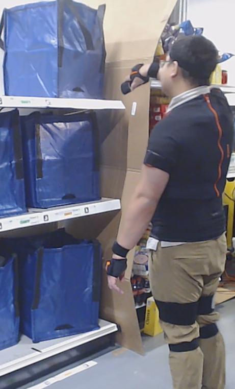 A man raising their arm while scanning the top shelf of storage boxes.